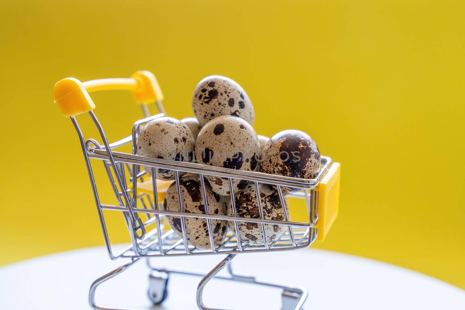 Happy Easter background. Easter quail eggs in the shopping cart on bright yellow paper. Festive concept.