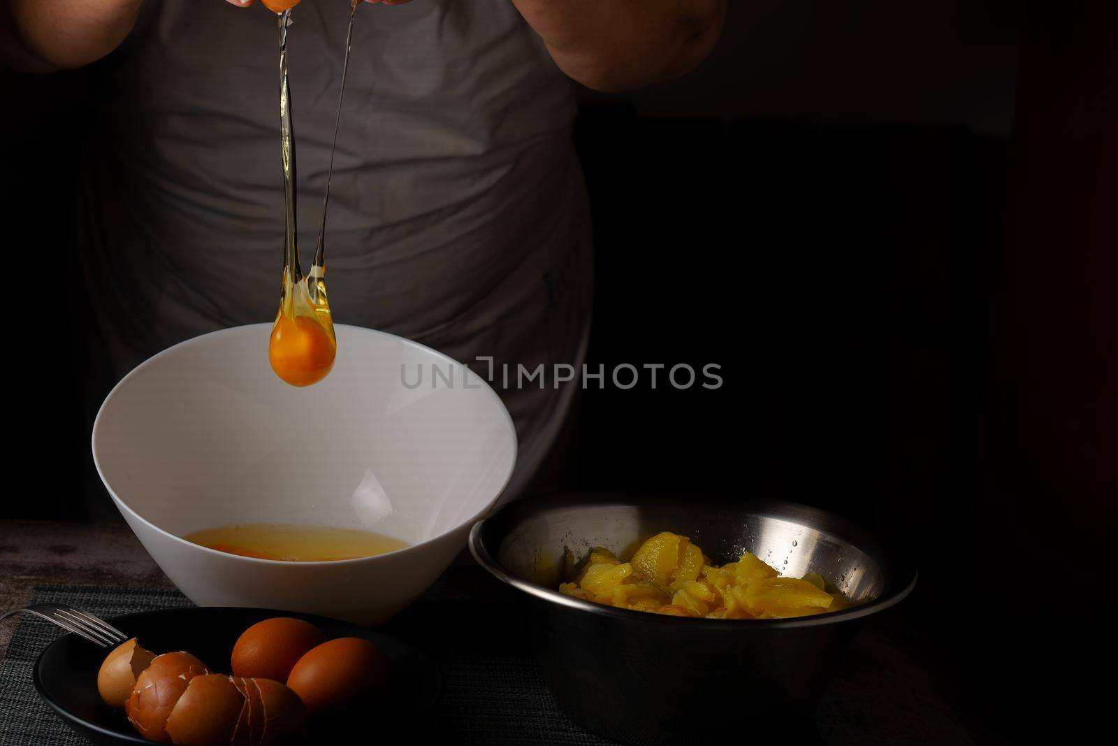woman in white apron cracking eggs into a bowl with the ingredients for a potato omelet