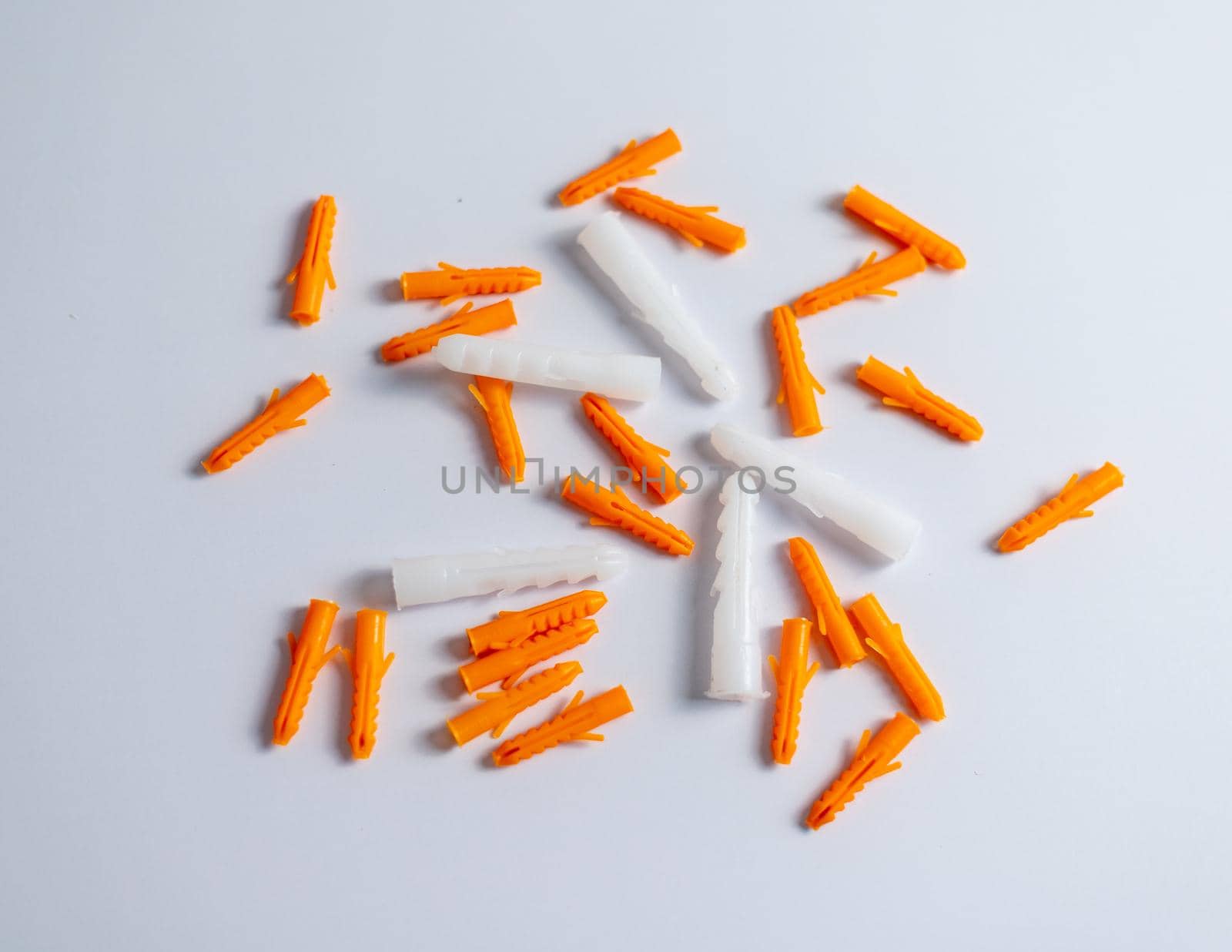 Plastic wall plugs or orange color dowel pin on white isolated background by Bilalphotos