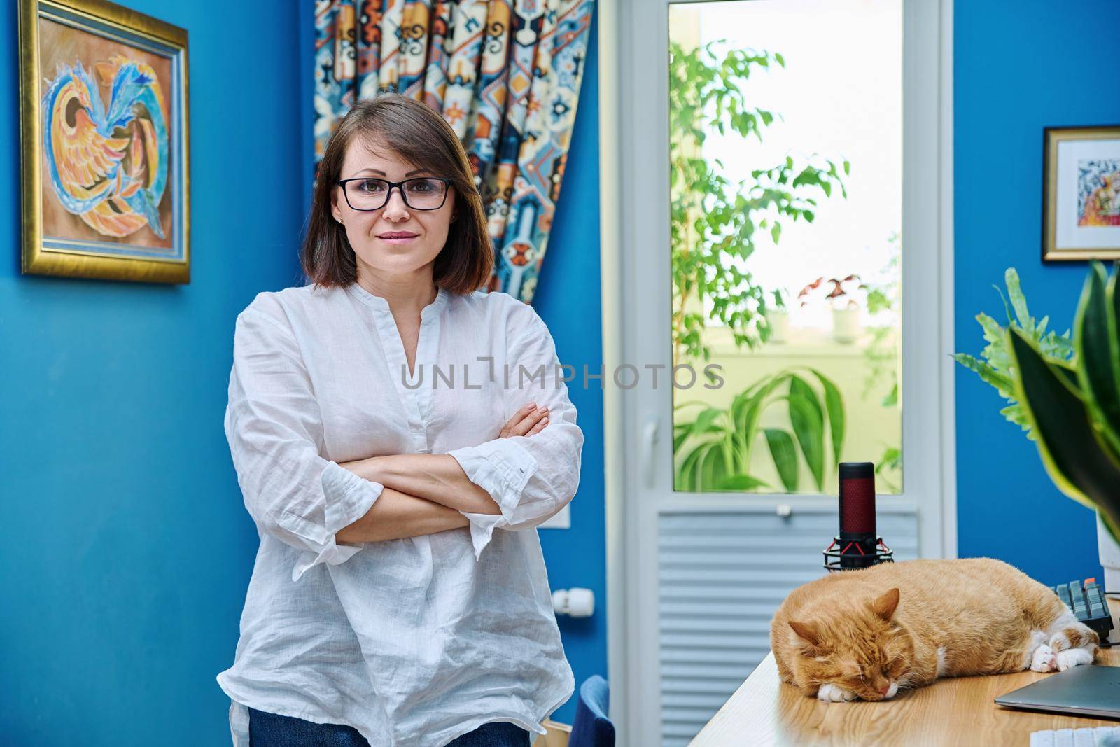 Confident middle aged woman in home office looking at camera by VH-studio