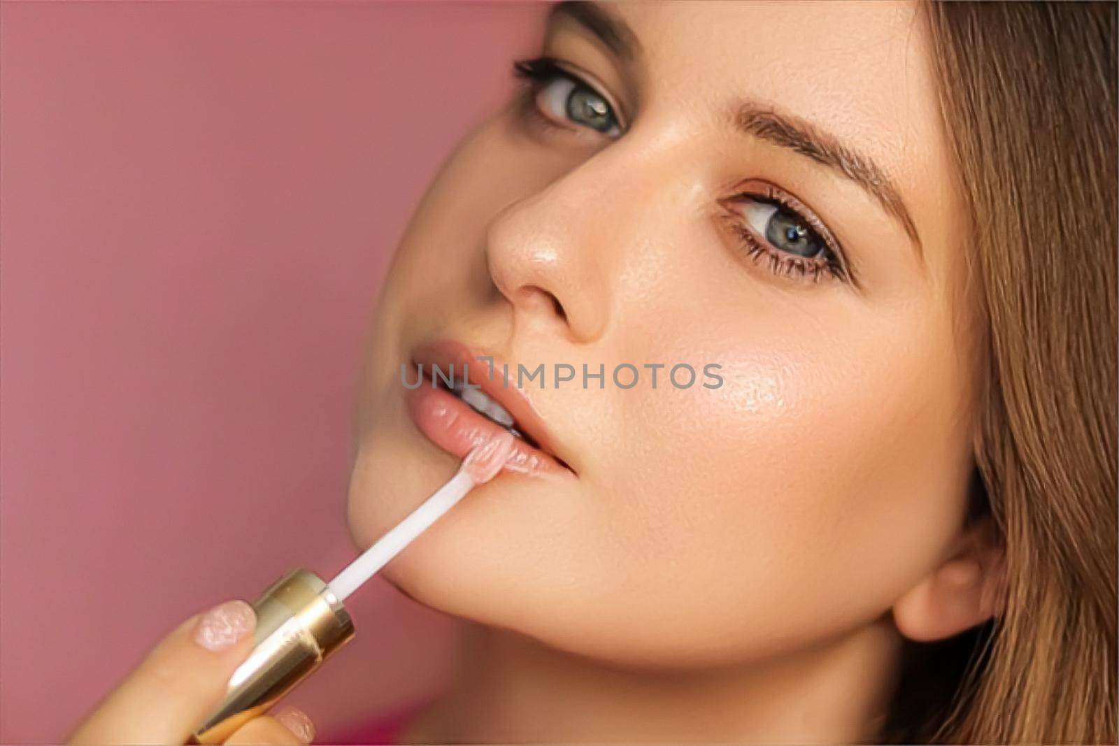Beauty, makeup and skincare cosmetics model face portrait on pink background, beautiful woman applying lip gloss, perfect healthy skin glow, facial care closeup
