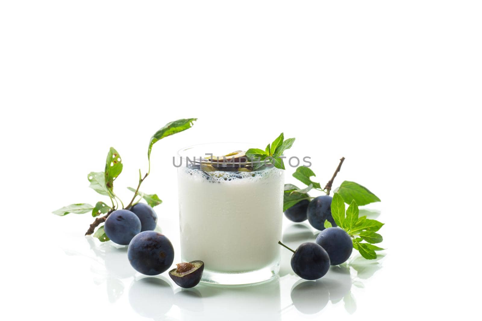 sweet homemade yogurt with fresh plum slices in a glass isolated on white background