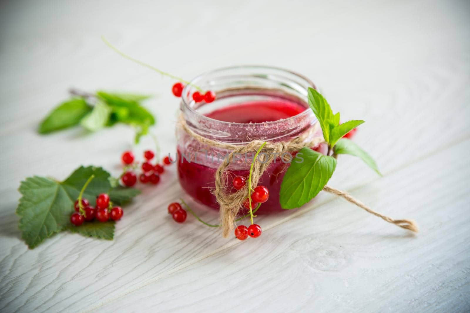 sweet summer jam from ripe red currants in a jar on a wooden table