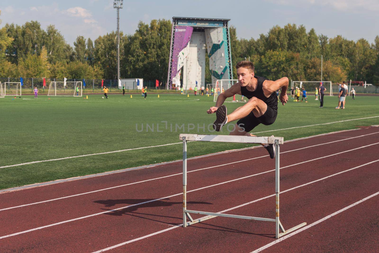 Young man athlete runnner running hurdles at the stadium outdoors