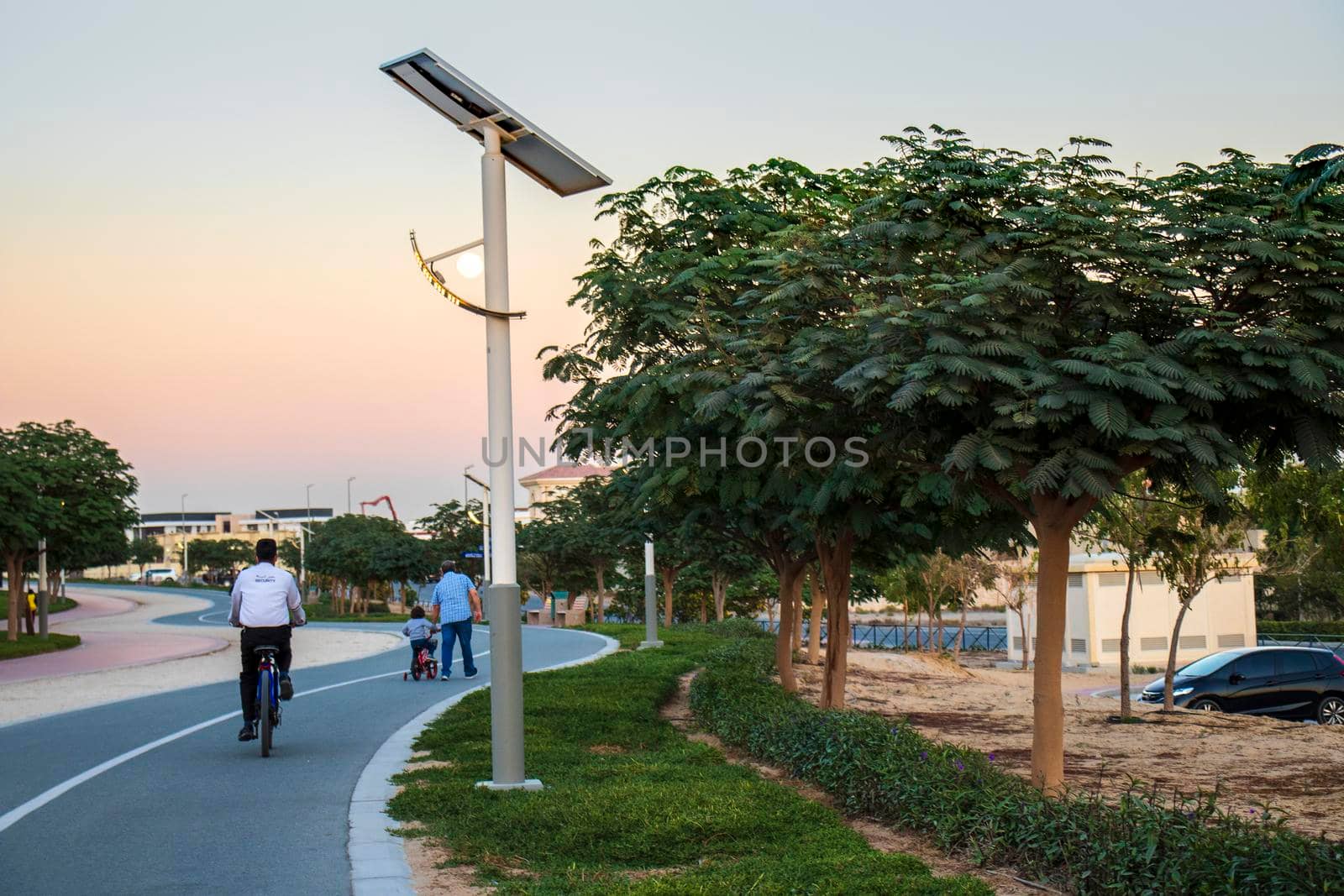 Jogging and cycling tracks in Al Warqa park, Dubai, UAE in the evening. Lamp post powered by solar panels can be seen in the picture.