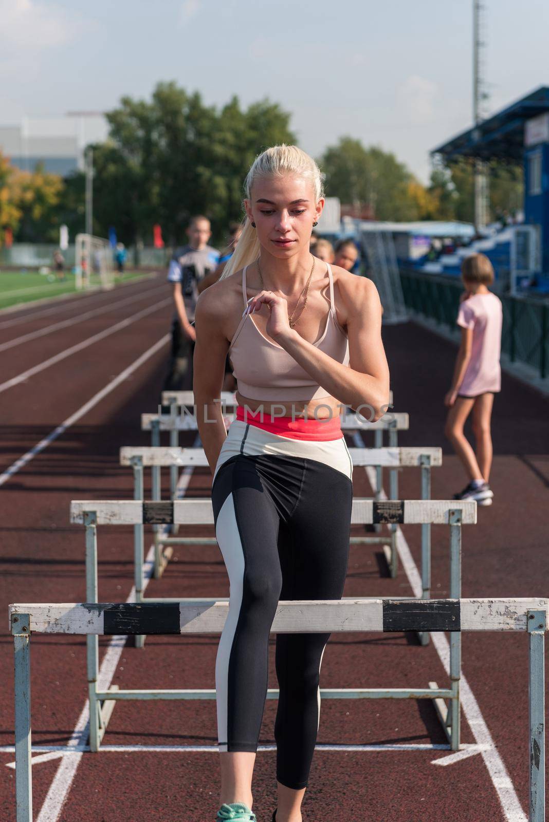 Young woman athlete runnner is exercising hurdles at the stadium outdoors