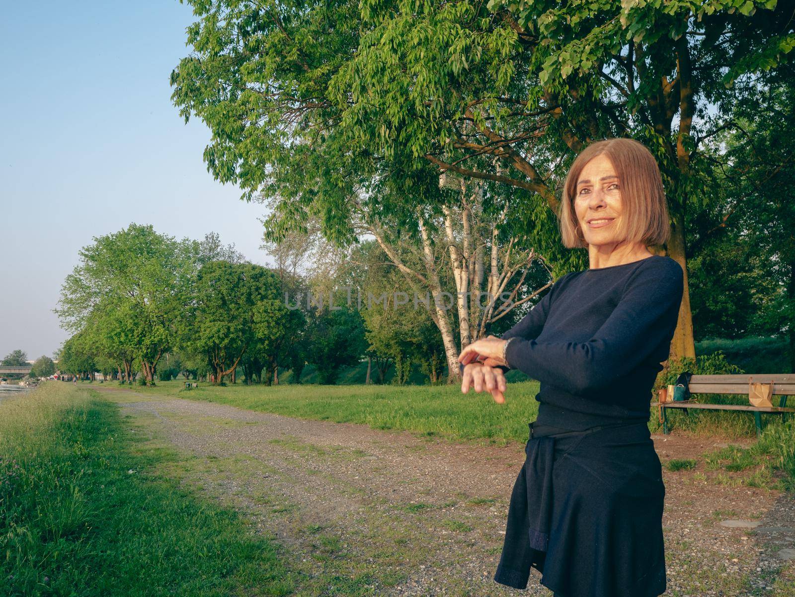 potrait of a senior woman in a park near a lake in spring time blue dressed by verbano