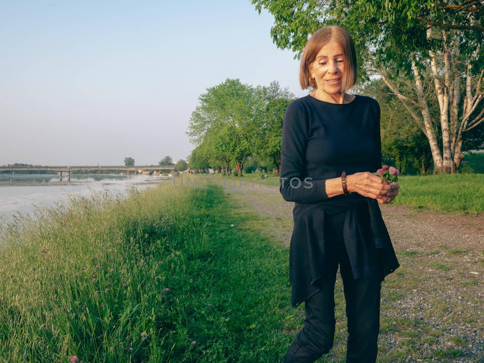 potrait of a senior woman in a park near a lake in spring time blue dressed by verbano