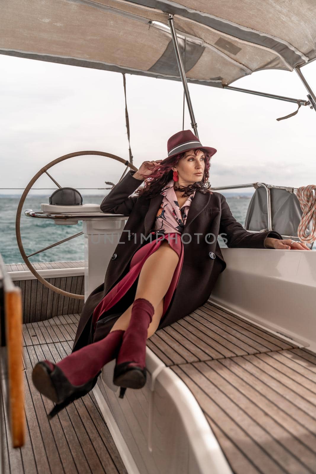 Attractive middle-aged woman at the helm of a yacht on a summer day. Luxury summer adventure, outdoor activities