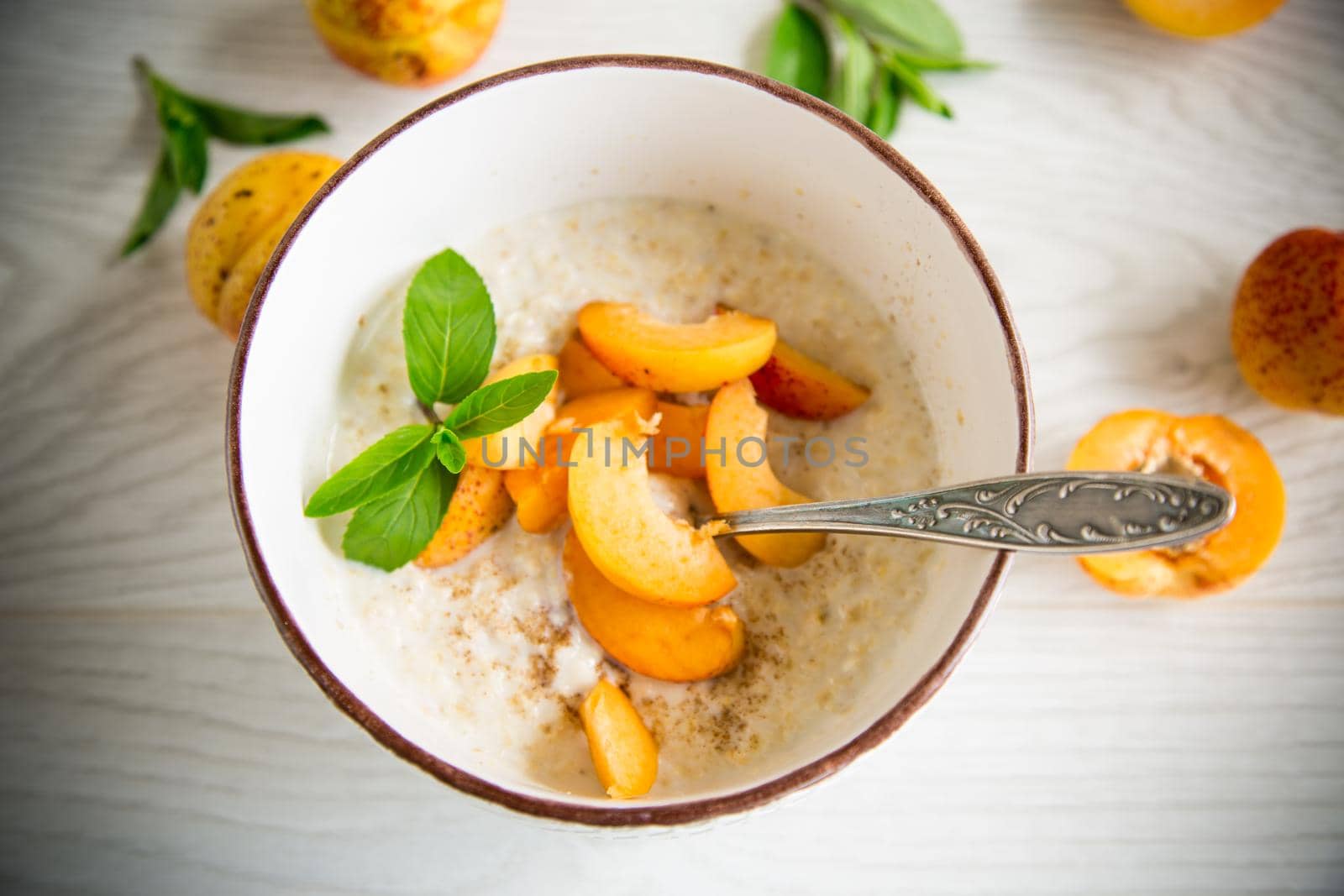 Healthy breakfast of boiled oatmeal with fresh apricots in a bowl on the table.