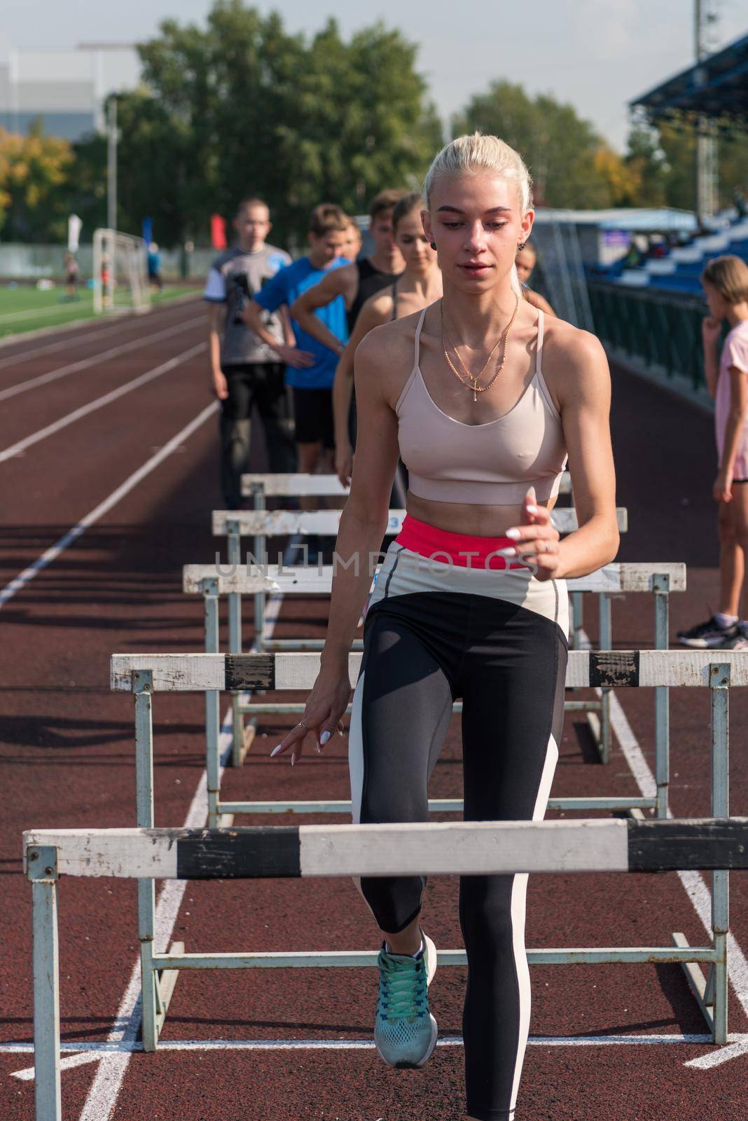 Young woman athlete runnner is exercising hurdles at the stadium outdoors