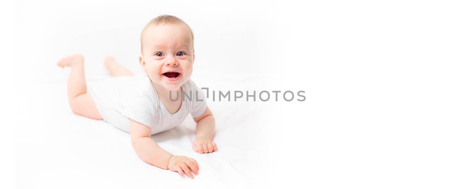 The baby lies on a white background and smiles at the camera . Advertising of children's goods. A child on a white background. Happy baby. The smile of a child. Children 's article . copy space