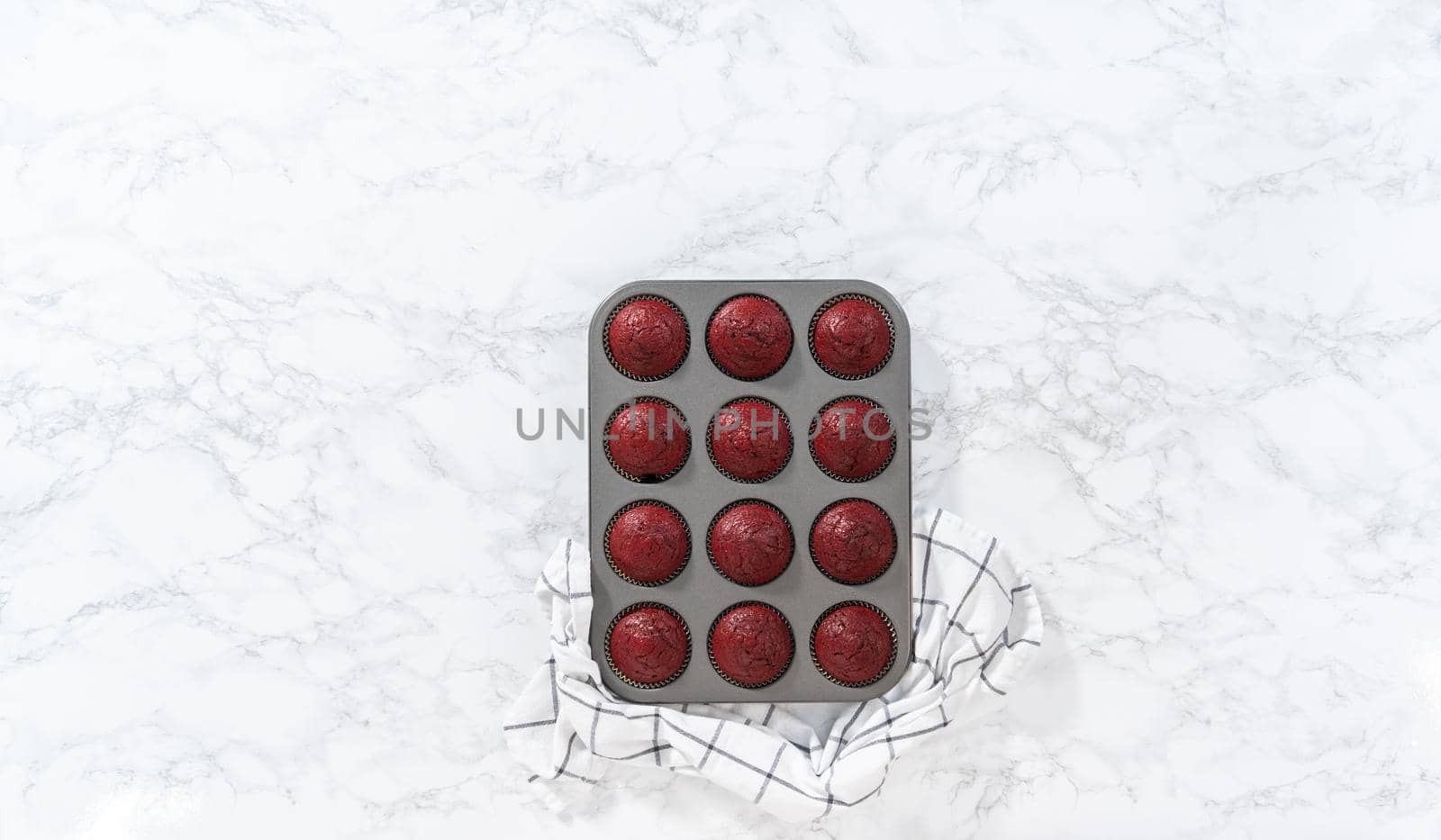 Flat lay. Cooling freshly baked red velvet cupcakes on a kitchen counter.