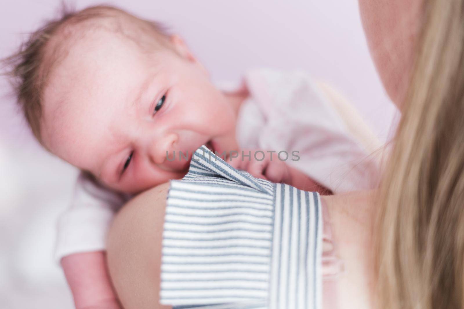 Lifestyle portrait of a young mother and her newborn, three weeks old daughter.