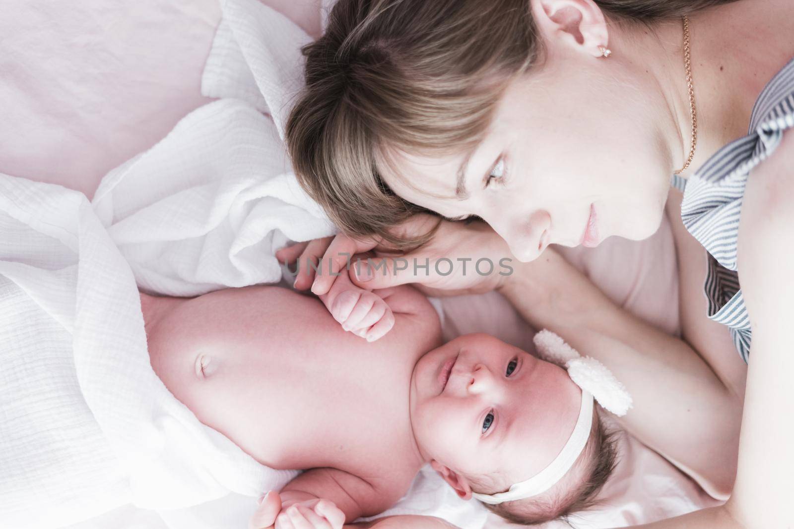 Lifestyle portrait of a young mother and her newborn, three weeks old daughter.