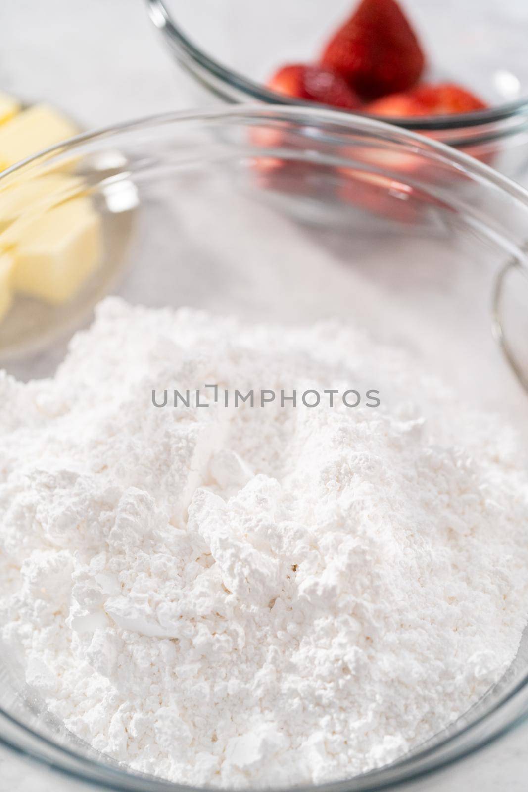 Ingredients in a glass mixing bowls to prepare the strawberry buttercream frosting.