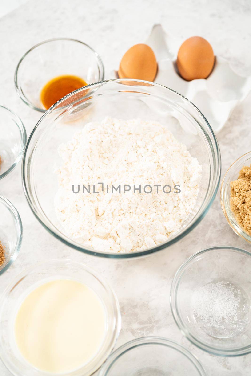 Measured ingredients in glass mixing bowls to bake eggnog scones.