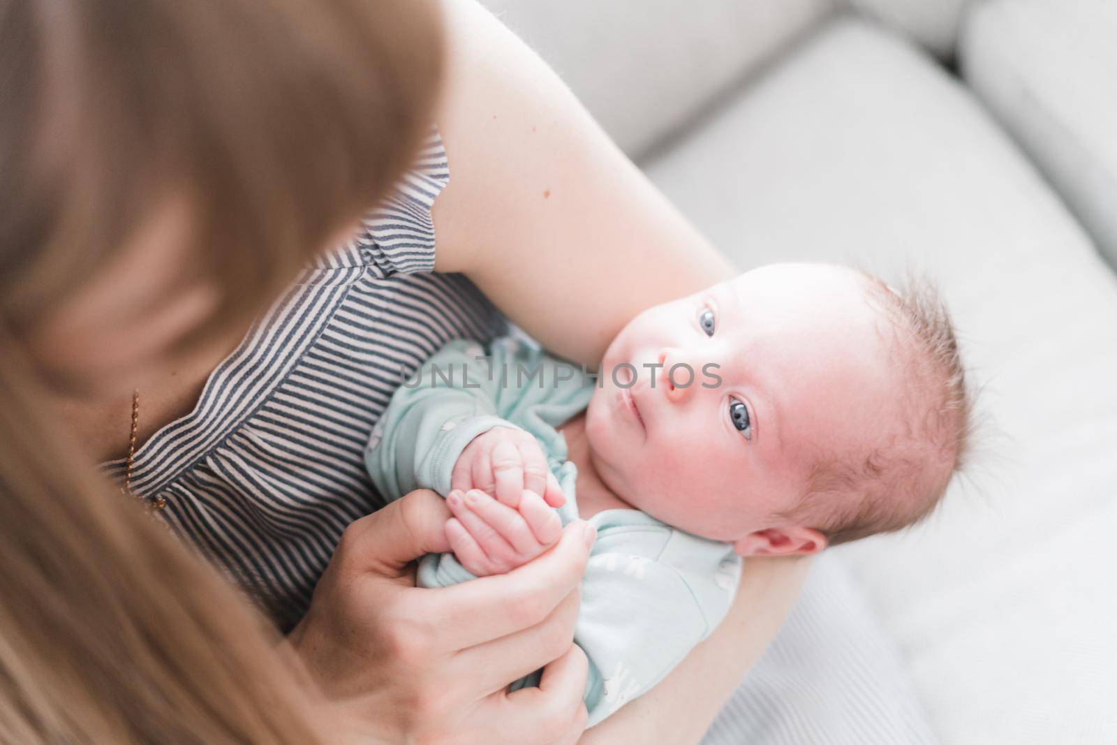 Lifestyle portrait of a young mother and her newborn, three weeks old daughter.