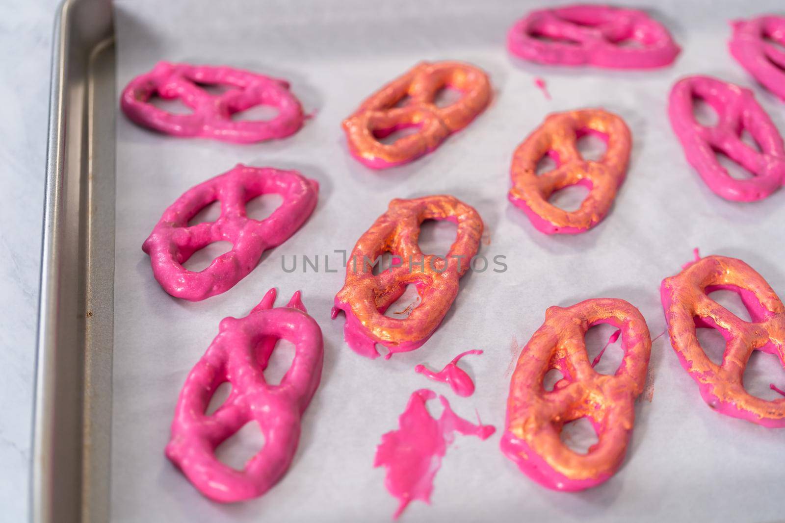 Painting chocolate-covered pretzel twists with glittery luster.