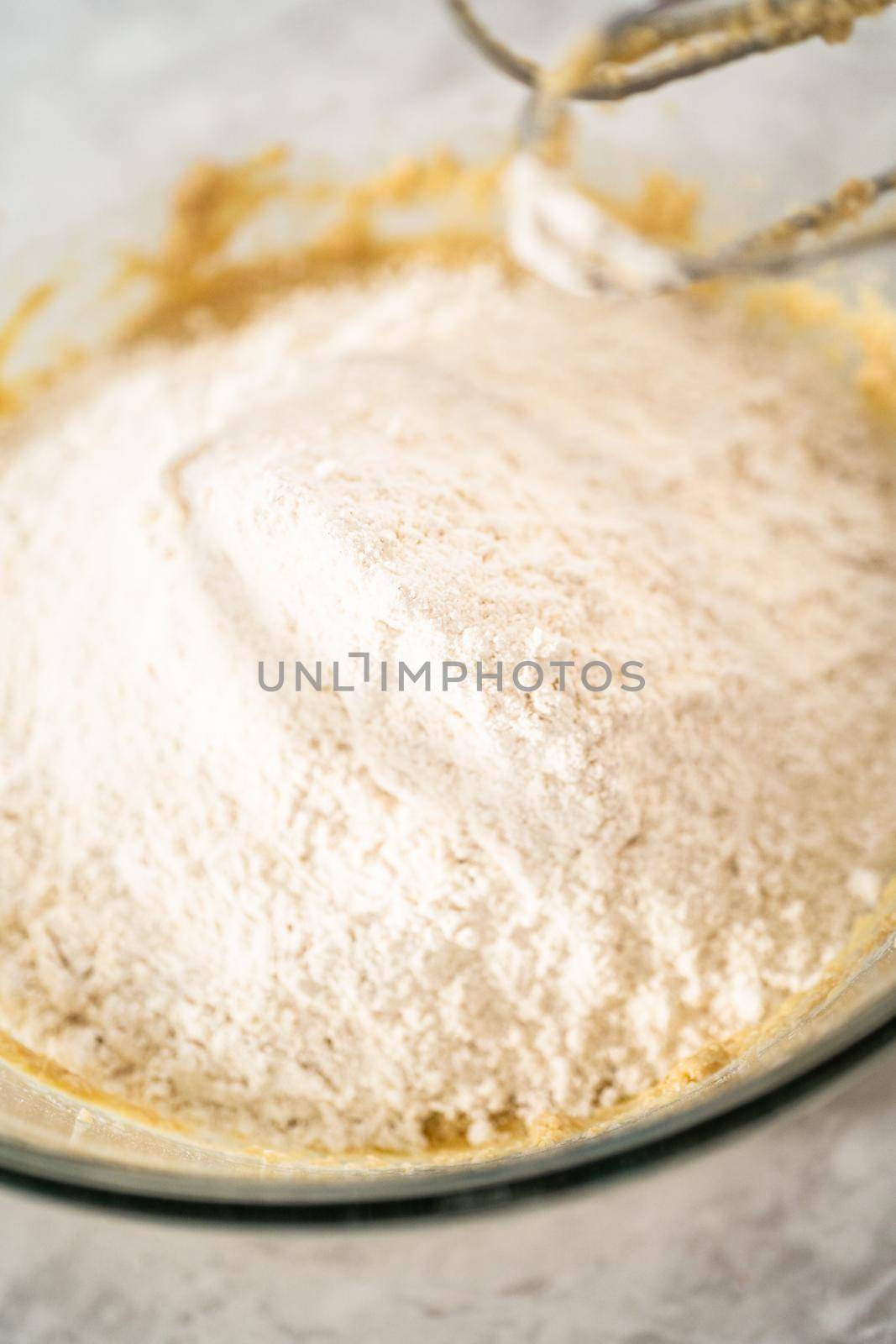 Mixing ingredients in a large glass mixing bowl to bake eggnog scones.