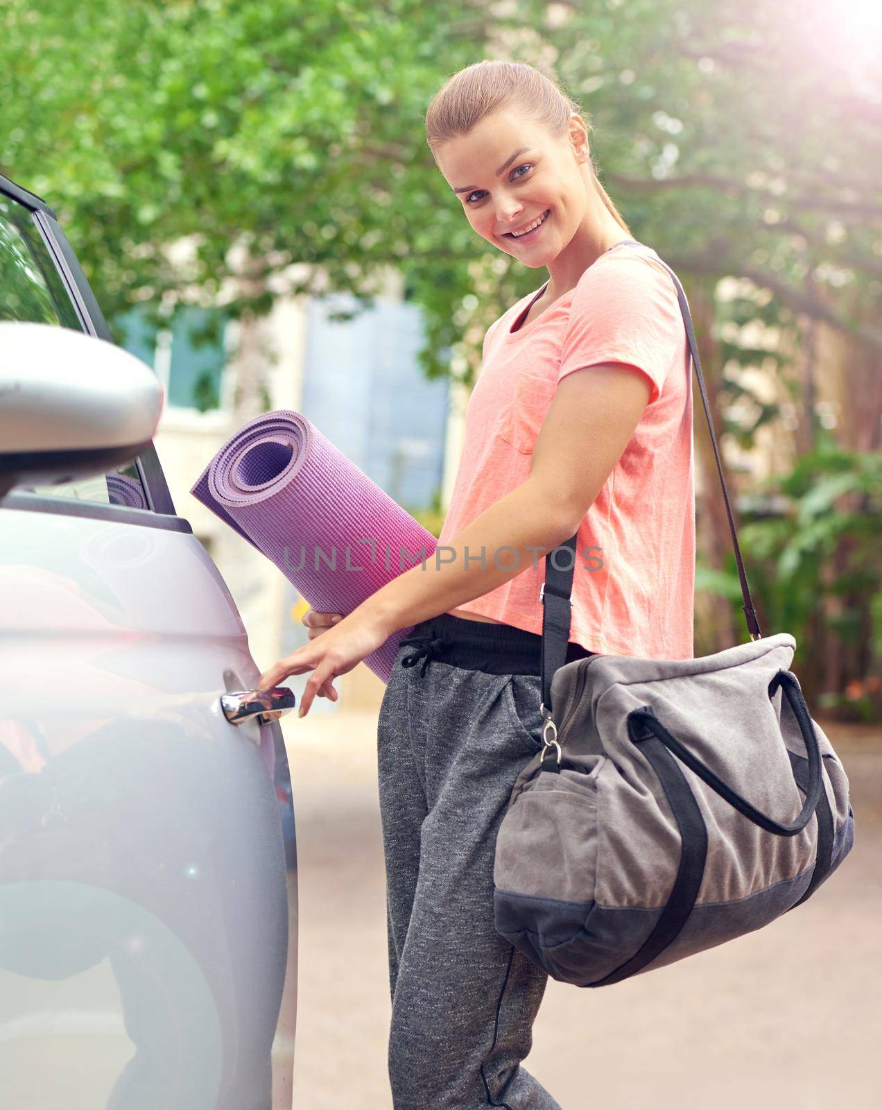 Yoga keeps me healthy and happy. a beautiful young woman carrying a yoga mat while getting into her car. by YuriArcurs