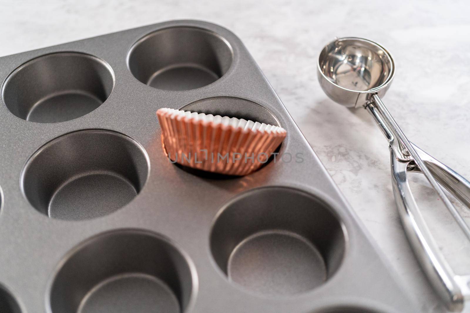 Scooping cupcake batter into the cupcake liners to bake chocolate strawberry cupcakes.