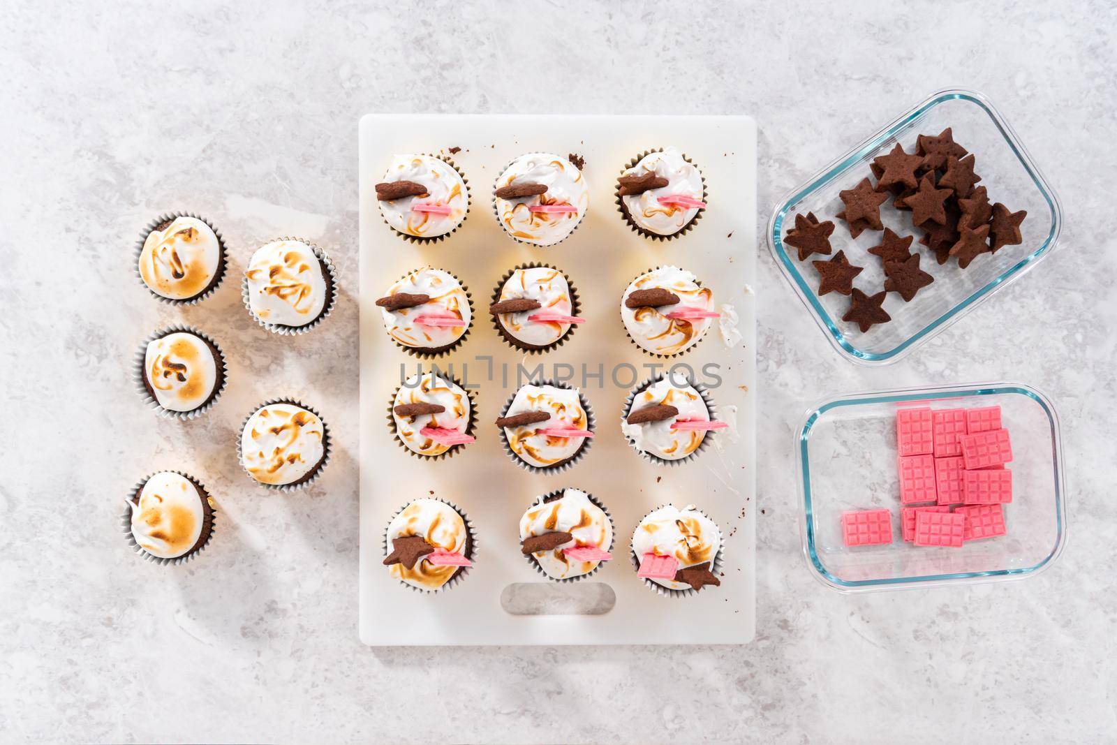 Flat lay. Gourmet s'mores cupcakes with meringue frosting and garnished with star-shaped chocolate graham cracker and a mini pink chocolate bar.