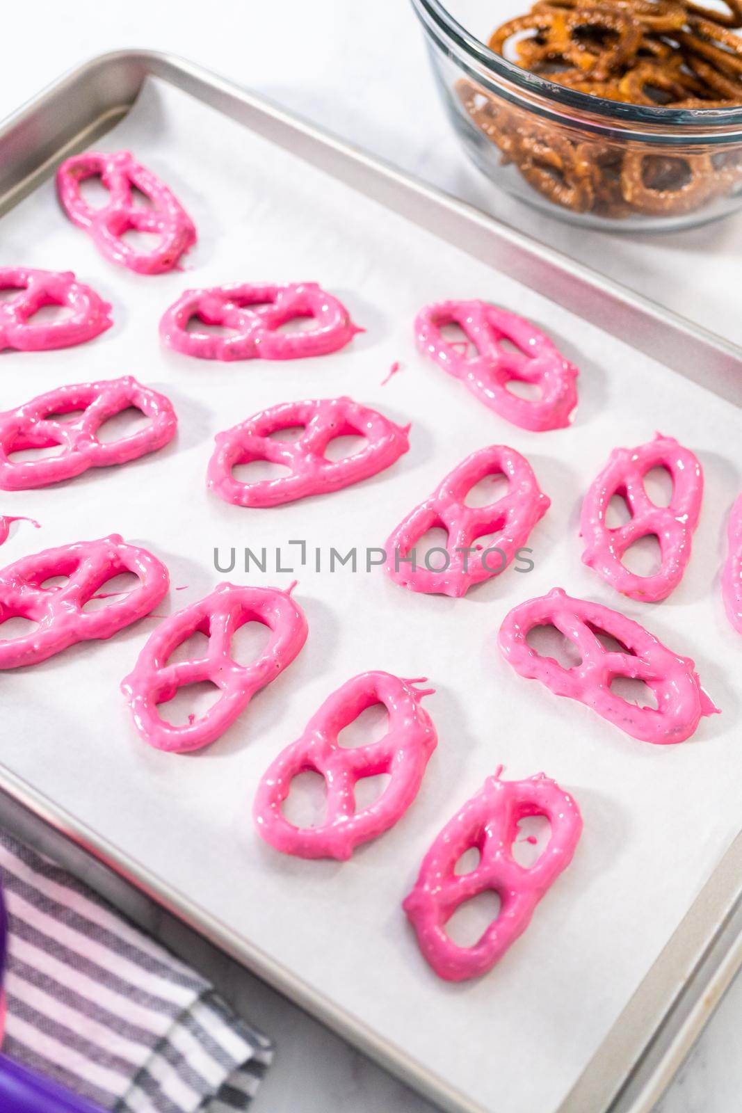 Dipping pretzels twists into melted chocolate to make chocolate-covered pretzel twists.