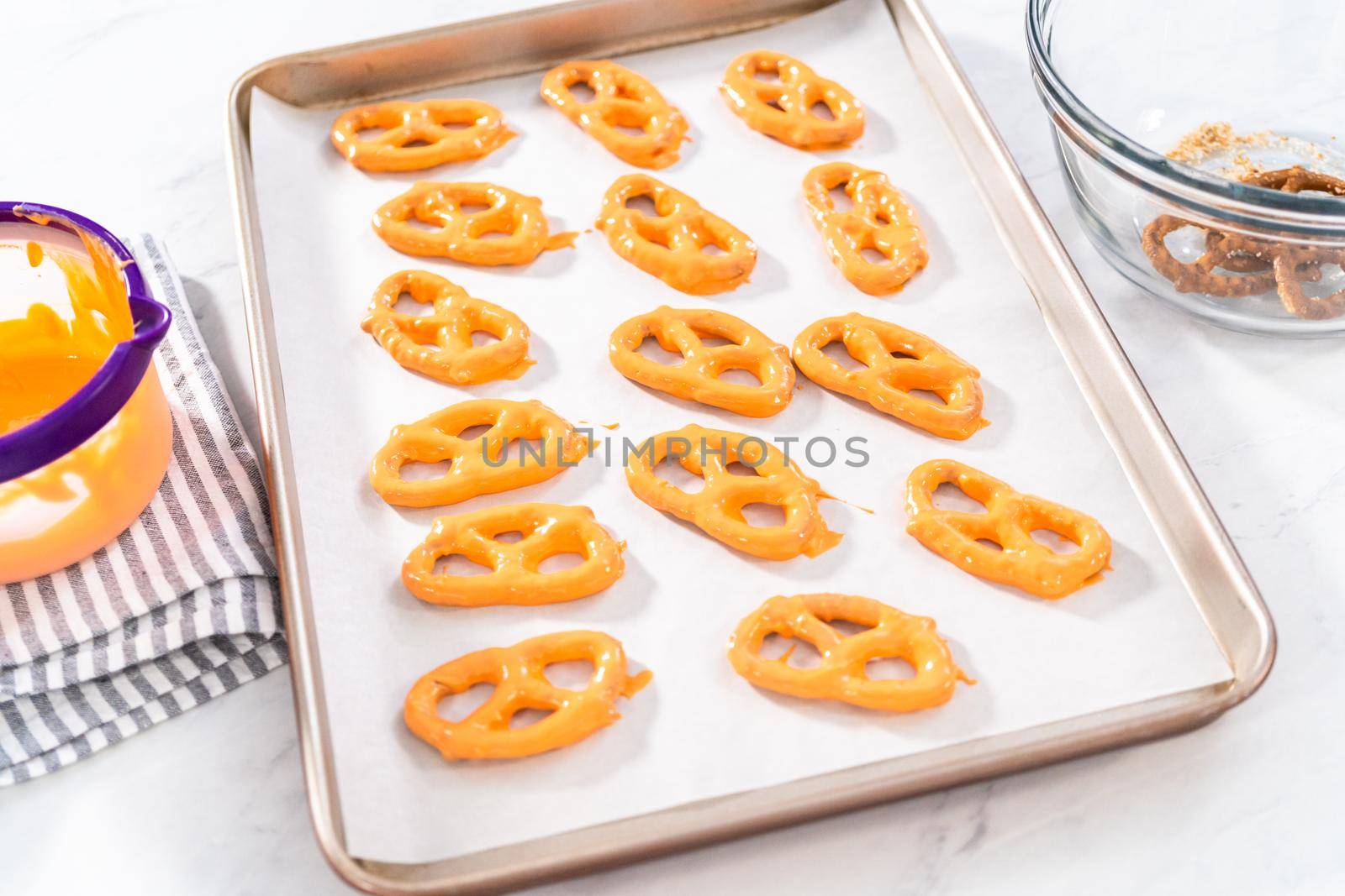 Dipping pretzels twists into melted chocolate to make chocolate-covered pretzel twists.