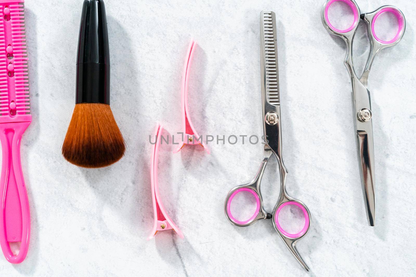 New barber set with pink scissors on a gray background.