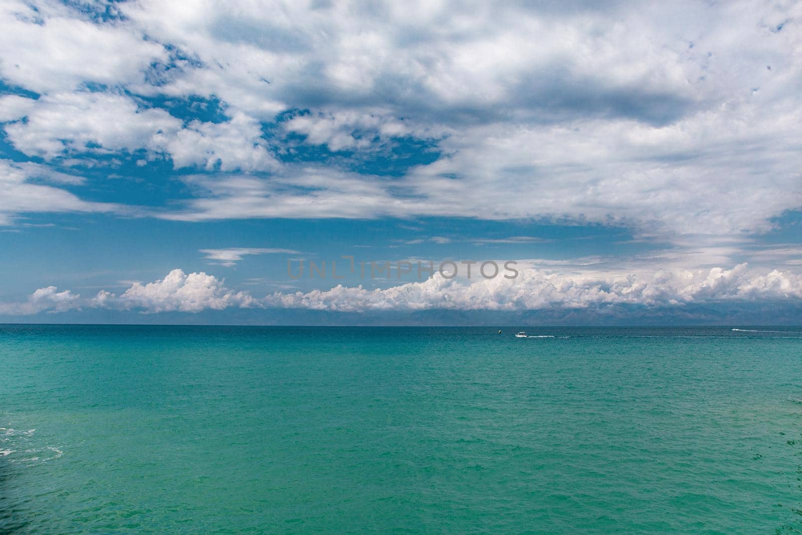 Beauty cloud against a blue sky background. Sky slouds. Blue sky with cloudy weather, nature cloud over the sea. Over the sea white clouds, blue sky and sun. High quality photo