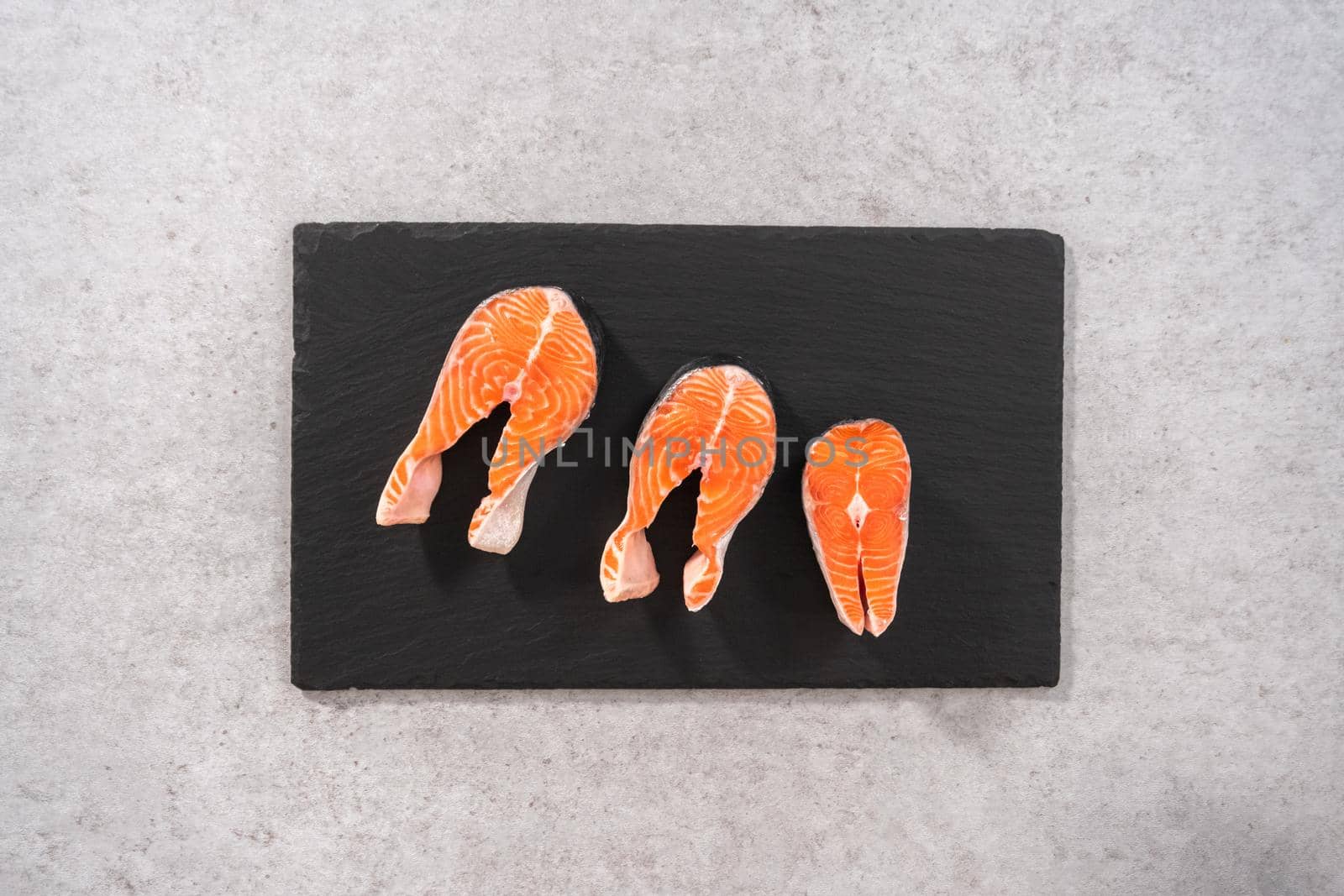 Flat lay. Farm-raised salmon steaks on a slate board.