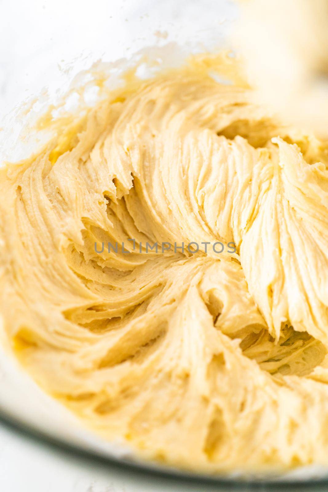 Mixing ingredients with a hand mixer in a large mixing bowl to bake mini vanilla cupcakes with ombre pink buttercream frosting.