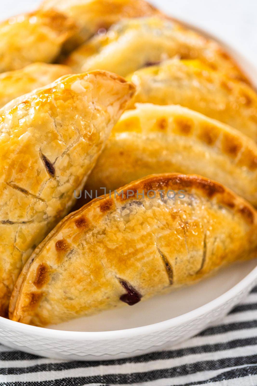 Freshly baked sweet empanadas with blueberries on the kitchen counter.