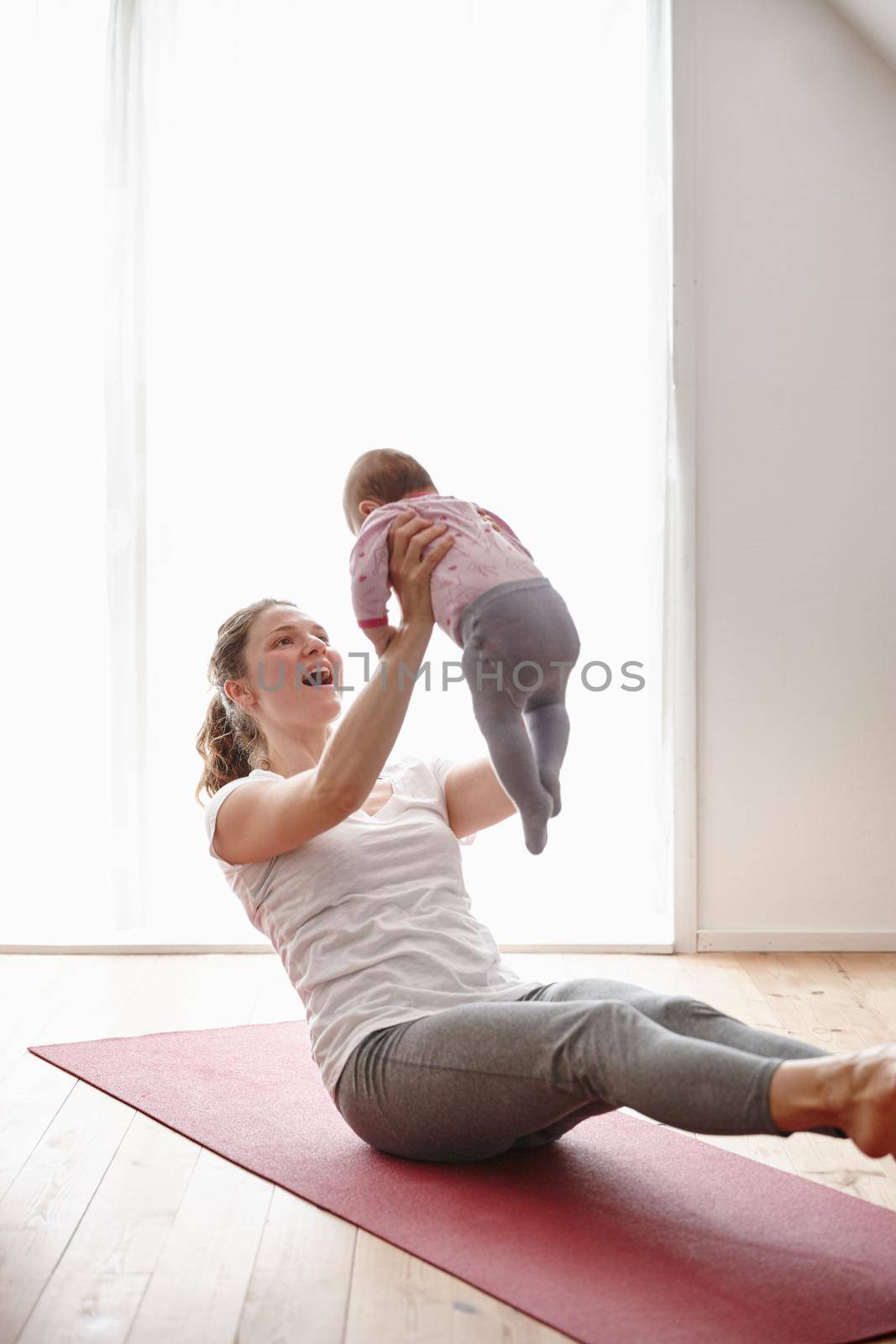 Yoga and baby-lifting the perfect workout. an attractive young woman bonding with her baby girl while doing yoga. by YuriArcurs