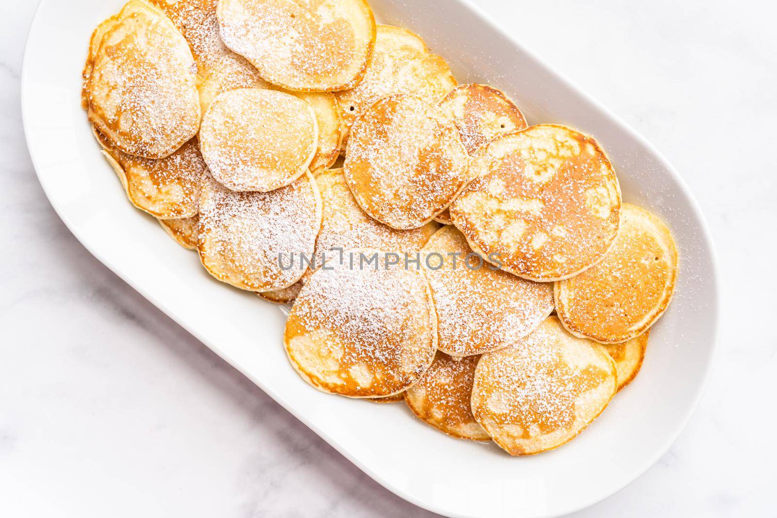 Flat lay. Freshly made small pancakes on a kefir base garnished with powdered sugar.