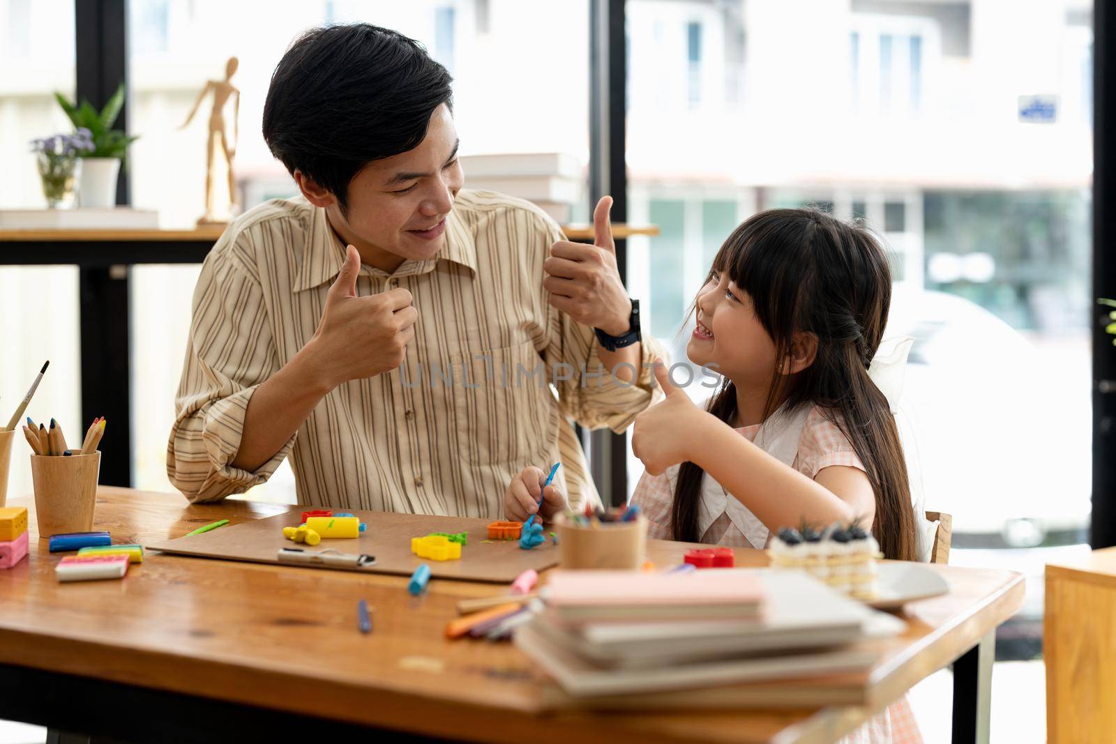 Proud asian father and daughter plasticine or play dough on a table dough together by nateemee