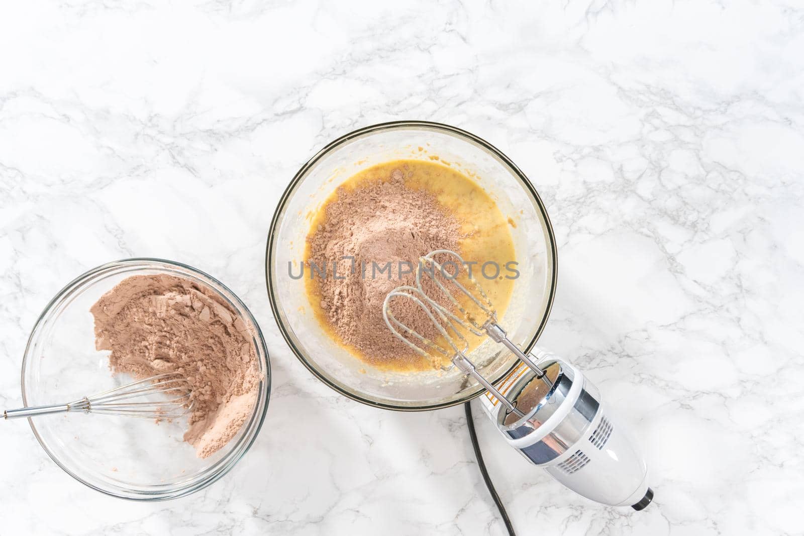 Flat lay. Mixing wet ingredients in a large glass mixing bowl to bake red velvet cupcakes with white chocolate ganache frosting.