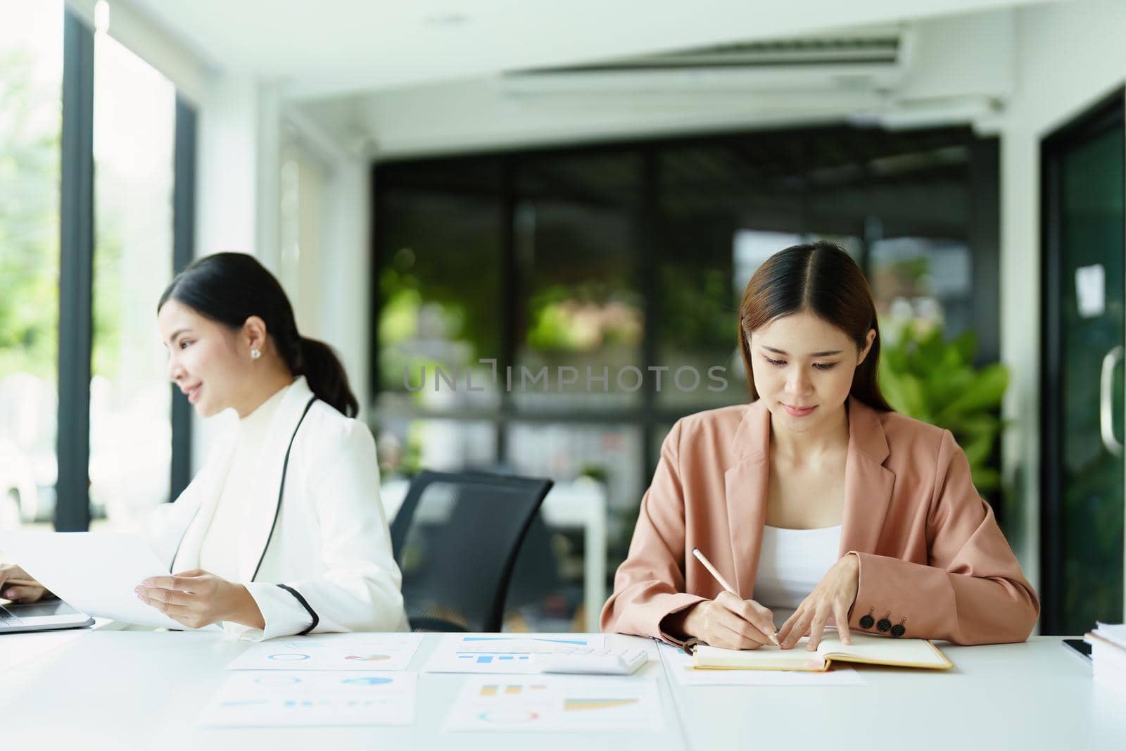 Portrait of a woman using notebooks and budget documents for work. by Manastrong