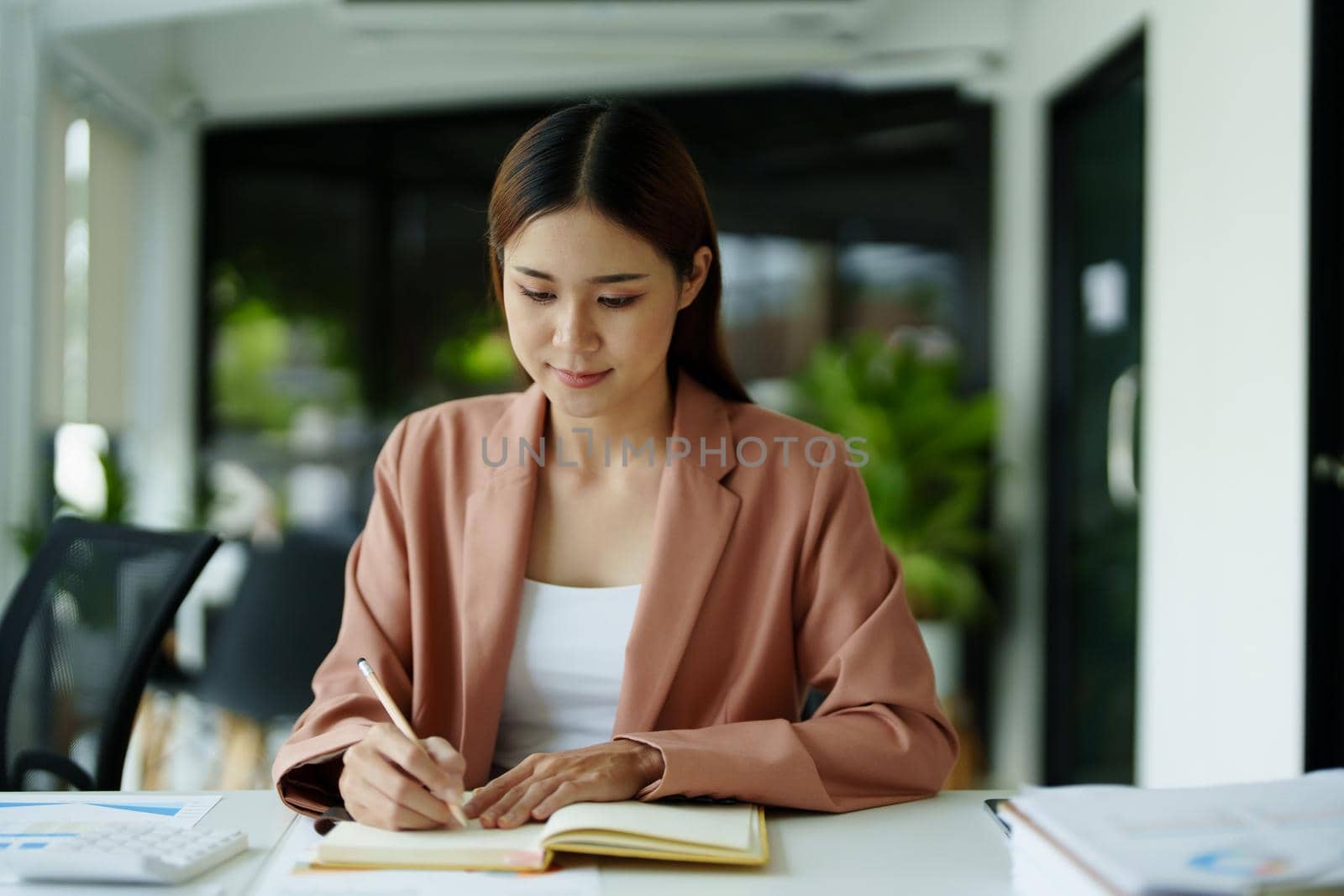 Portrait of a woman using notebooks and budget documents to work on analyzing marketing plans and making plans to increase company profits.