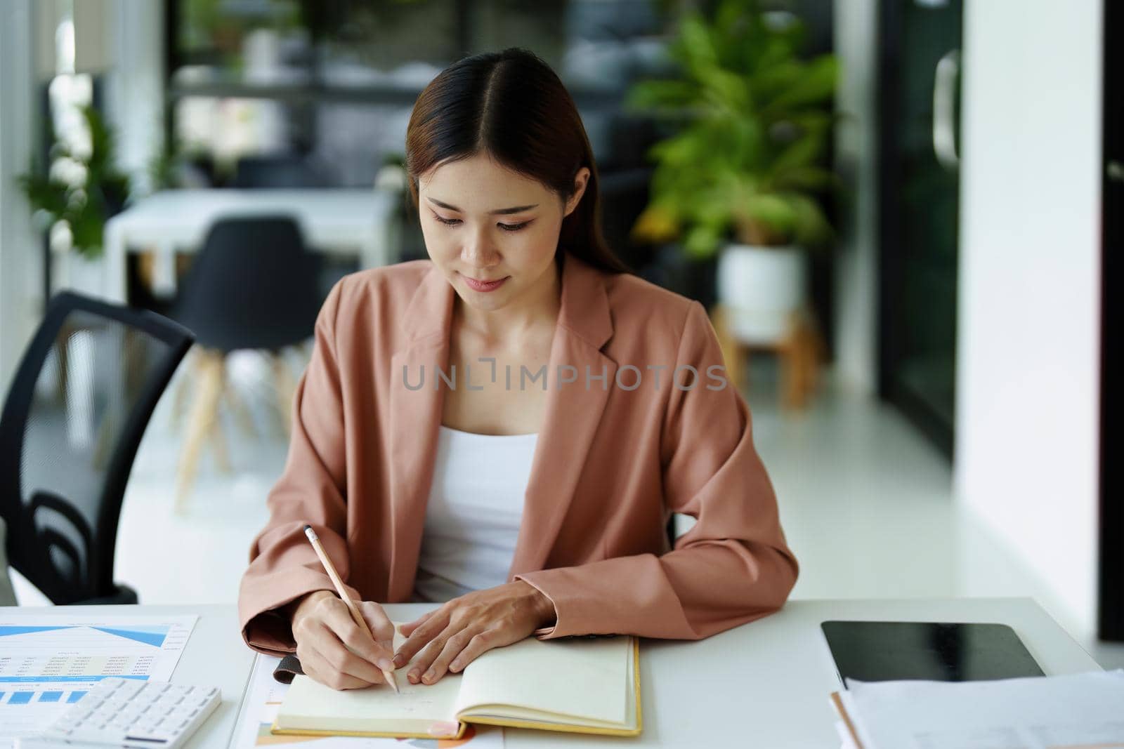 Portrait of a woman using notebooks and budget documents for work. by Manastrong