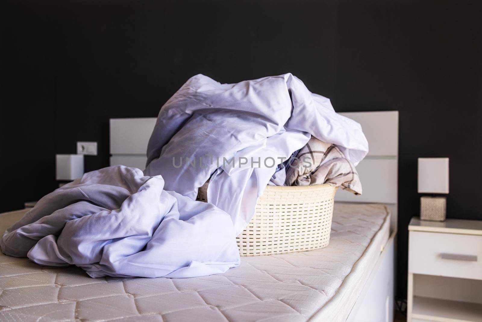A large pile of dirty linen on the bed is collected in a basin to be washed. The concept of homework, cleaning in the apartment, studio, apartment booking. Laundry concept, liquid bed linen detergent
