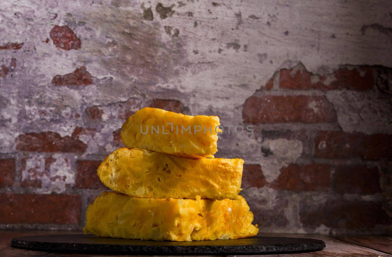 several servings of typical Spanish tortilla de patatas (potato omelet) stacked on a black slate plate
