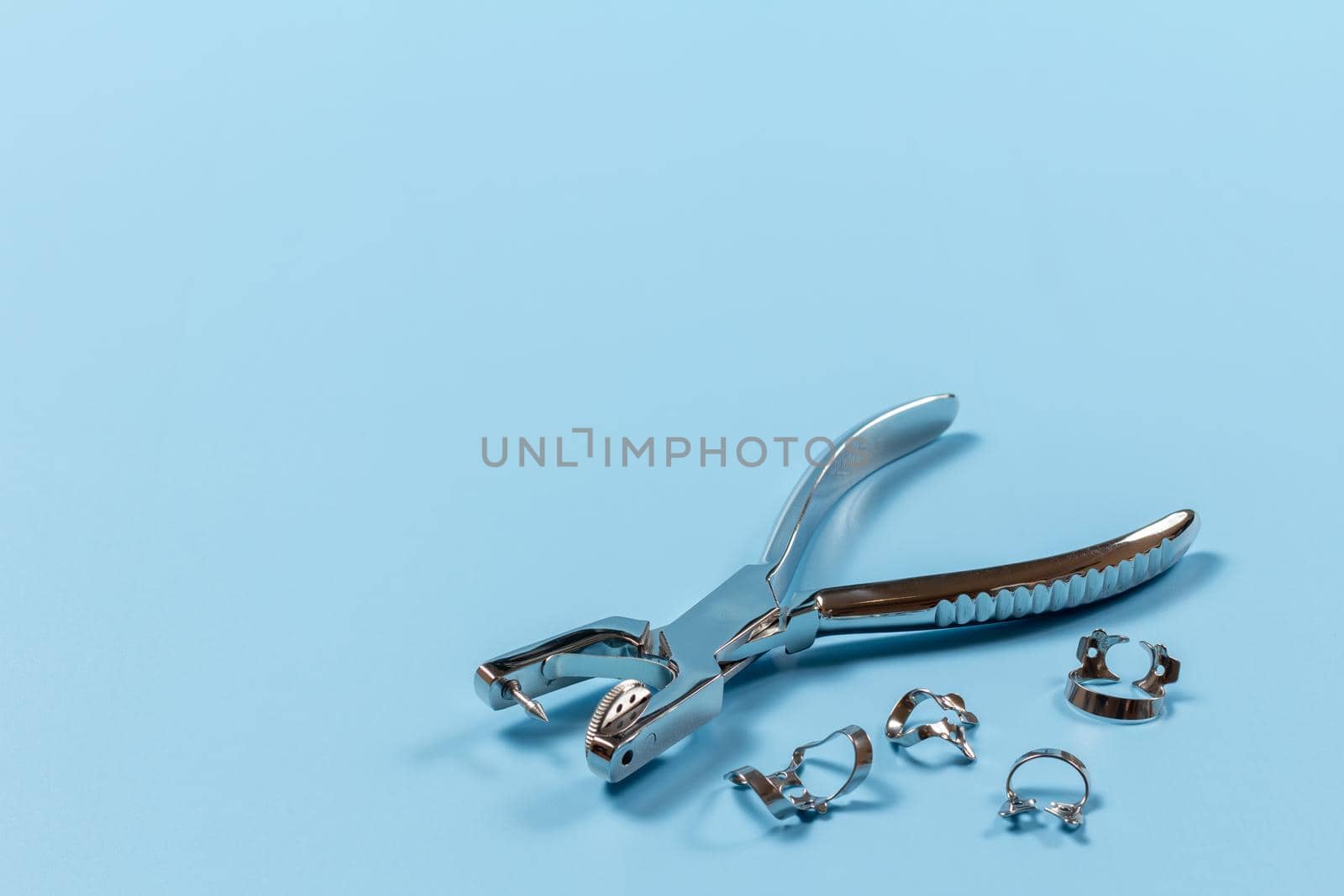 Dental hole punch and clamps on blue. by mvg6894