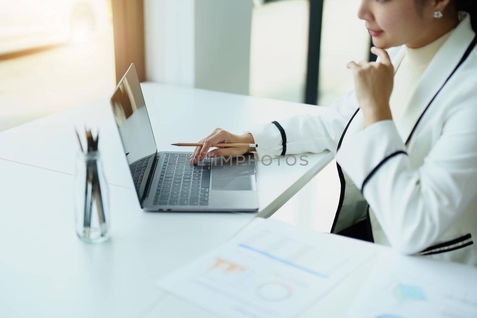 Portrait of a woman using a computer with budget documents to work on analyzing marketing plans and making plans to increase company profits.