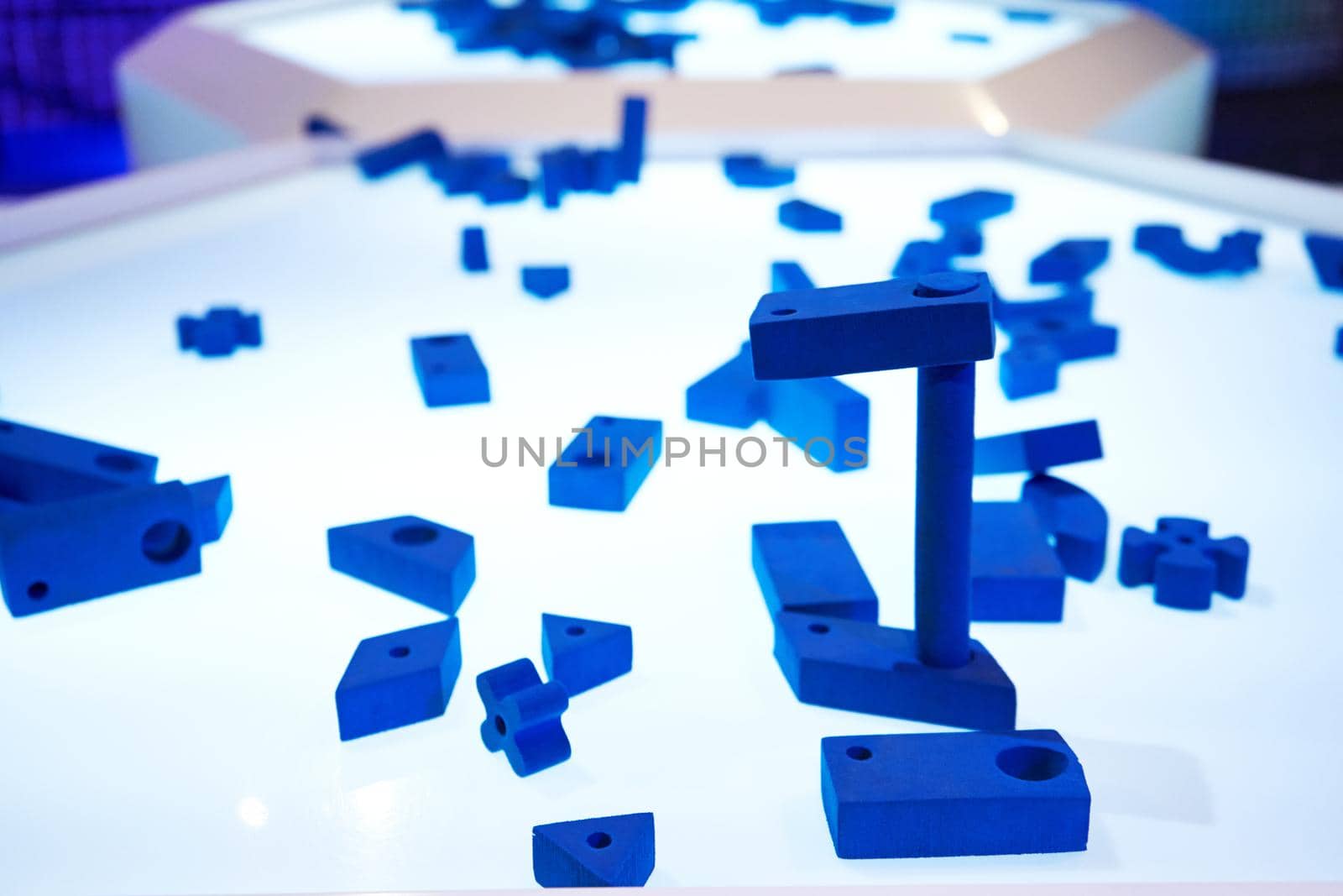 Parts of blue 3d puzzle on glowing table.
