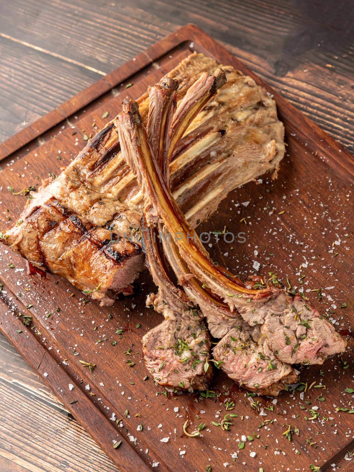 Grilled lamb chops on a wooden serving plate by Sonat