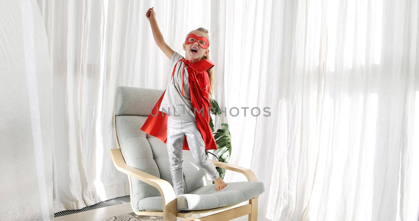 Little girl in superhero costume with mask playing in living room by Demkat