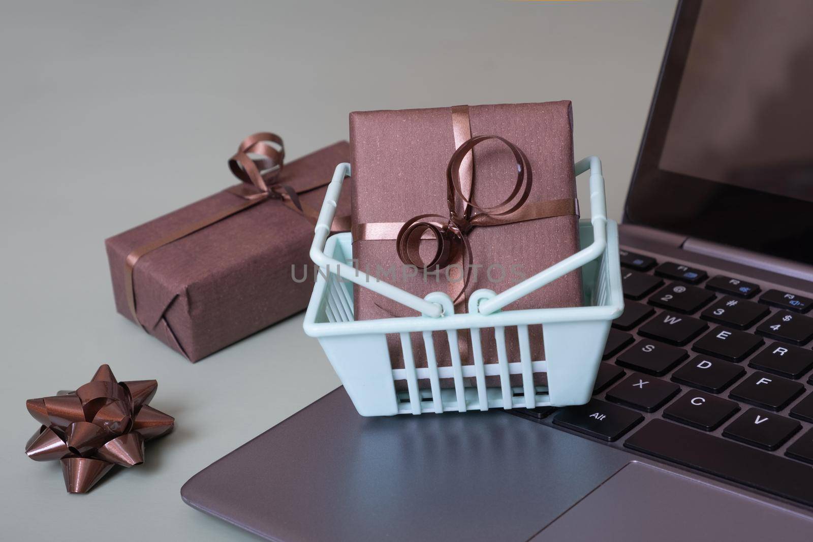 Wrapped gifts in shopping baskets on laptop. Online shopping concept.