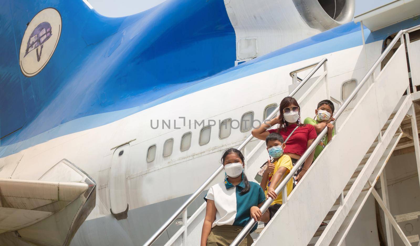 All the families were wearing masks to stand on the stairs for boarding the plane.